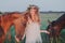 Smiling girl in floral wreath with horse. Wheat field