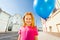 Smiling girl with flying balloon stands on street