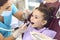 Smiling girl getting cavity tooth cure from woman dentist in clinic