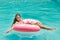 Smiling girl have fun floating on inflatable donut in blue swimming pool