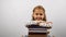 Smiling girl holding a pile of books looking into the camera.