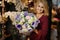 Smiling girl holding a spring bouquet of tender purple, green and rosy color flowers in the wrapping paper