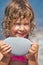 Smiling girl holds in hands pebble on seacoast