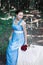 Smiling girl keeps bouquet of red roses and sits down on a table