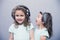 Smiling girl listening to music in headphones with sister scream