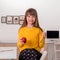 A smiling girl with long hair and bangs   puts breakfast - an apple and a banana in a school backpack