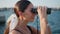 Smiling girl looking binoculars at summer embankment closeup. Happy trendy woman