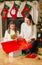 Smiling girl and mother wrapping Christmas gifts in red paper an