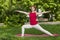 Smiling girl in the park exercise on the yoga mat, high lunge