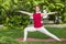 Smiling girl in the park exercise on the yoga mat, high lunge