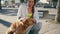 Smiling girl petting dog summer boulevard. Woman stroking pet sitting longboard