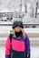 Smiling girl in pink ski jacket and hat with snow
