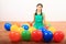 Smiling girl playing kneeling among inflating balloons