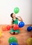 Smiling girl playing kneeling among inflating balloons