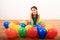 Smiling girl playing kneeling among inflating balloons