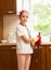 Smiling girl posing on messy kitchen with broom and scoop