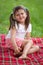 Smiling girl preschooler sitting on plaid in park