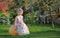 Smiling girl on pumpking over apple tree on a farm