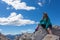 Smiling girl sitting on a boulder looking at the sky in the Dolomites