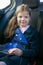 Smiling girl sitting in a car wearing a seat belt in a child seat