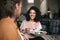 Smiling girl sitting in restaurant with friend. Beautiful African American lady sitting at cafe with salad in hand