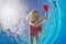 Smiling girl swimming underwater in pool for tropical red flower
