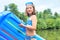 Smiling girl in swimwear standing with pool raft at lakeshore