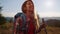 Smiling girl trekking in mountains at summer. Female traveler hiking in field