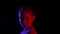 Smiling girl turning around and looking to camera in dark studio with red and blue lighting. Beautiful girl posing front