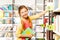 Smiling girl with two braids standing near shelf