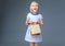 Smiling girl in white dress on grey showing shopping bag