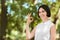 A smiling girl in a white shirt on a nature background. Beautiful girl making an `OK` sign. A happy lady in a park.