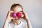 Smiling girl in a white t-shirt closes her eyes with multi-colored Easter painted eggs. Happy child celebrates easter