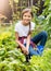 Smiling girl working at garden and digging out fresh green lettuce