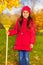 Smiling girl with yellow rake stands in park