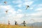 Smiling girls and brother boy with flying colorful kites - popular outdoor toy on the high grass mountain meadow. Happy childhood