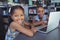 Smiling girls with laptop at desk in library