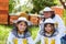 Smiling girls with male apiarist wearing protective suits