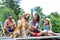 Smiling girls stroking Golden retriever while sitting with family on pier