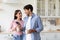 Smiling glad millennial female and male with cups of hot drink talk in modern kitchen