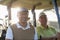 Smiling golfer friends sitting in golf buggy