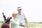 Smiling golfers standing at golf course against clear sky