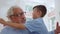 Smiling grandfather looking at grandson. Joyful boy sitting on grandparent laps