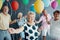 Smiling grandmother wearing a white blouse with black dots and holding colorful balloons during New Year`s Eve party with senior