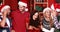 Smiling group of friends standing together wearing santa hat