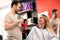 Smiling hair styling with his blonde costumer at beauty salon