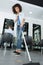 Smiling hairstylist sweeping hair clippings on floor in salon