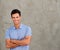 Smiling handsome man standing by wall with arms crossed