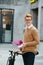 Smiling handsome young man with ebike and phone on the street.