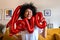 Smiling, happy African American mixed race woman holding red love foil balloon. Funny face.